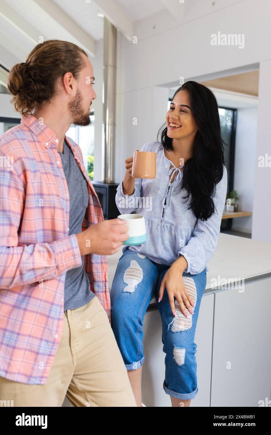Diverse Paare genießen Kaffee in der Küche zu Hause. Sie hat langes schwarzes Haar, hellbraunes Haar und Bart, unverändert Stockfoto