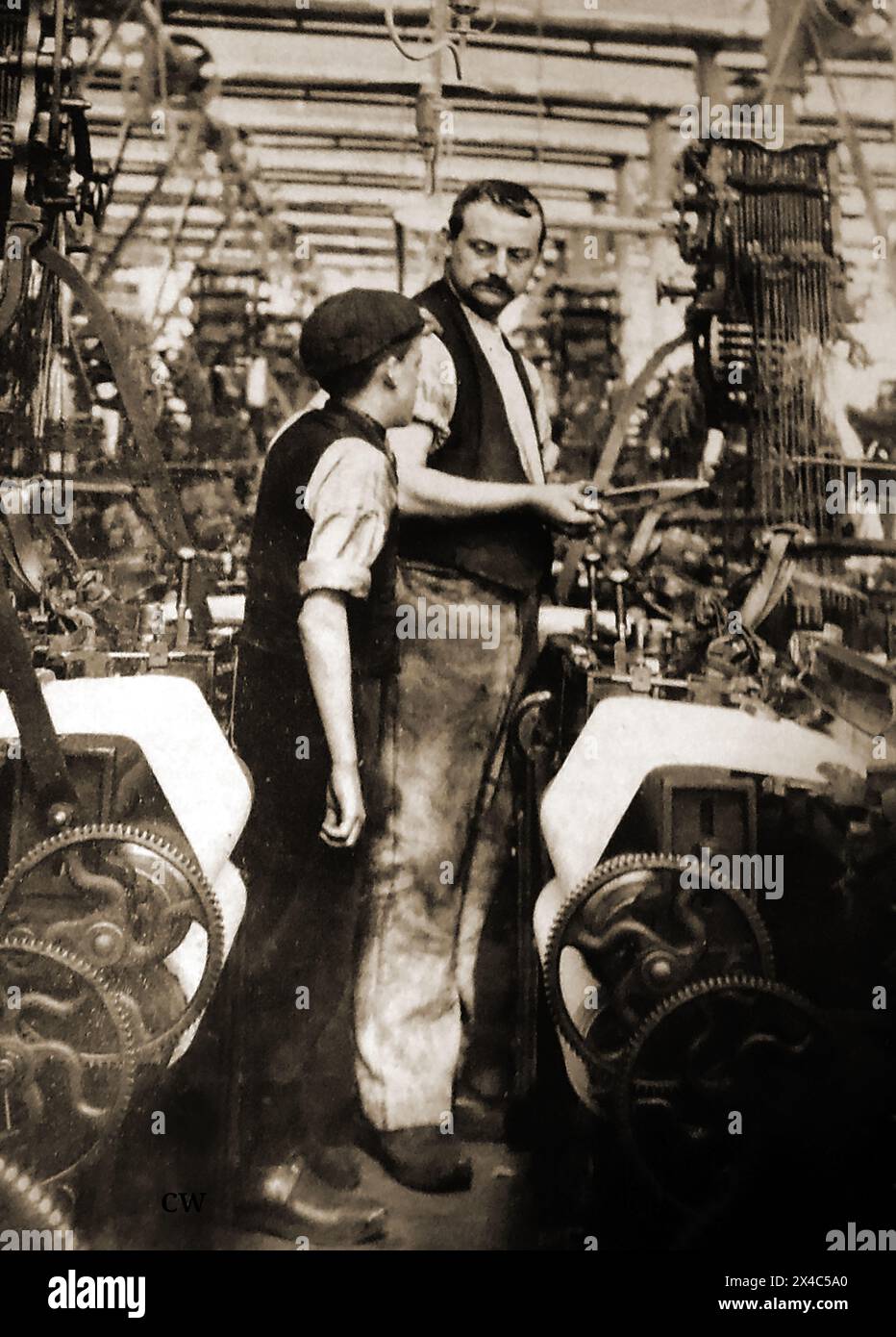 Ein britischer Arbeiter, der einen Lehrling in einer Baumwollmühle ausbildet. C1900.j Stockfoto