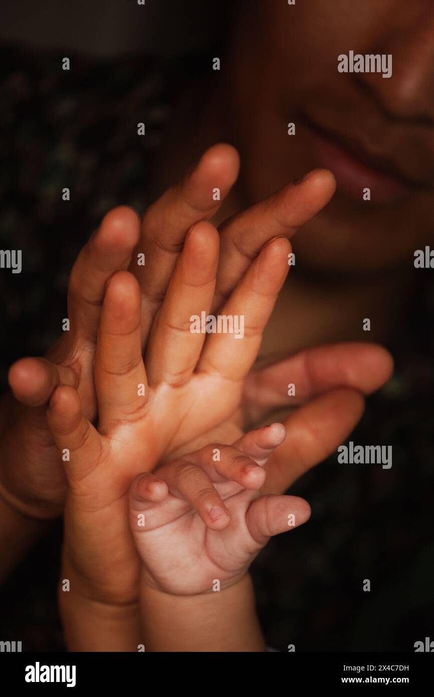 Nahaufnahme der Hände einer Familie, die in einem warmen, intimen Moment die Verbindung zwischen Vater, Mutter und Baby zeigt Stockfoto