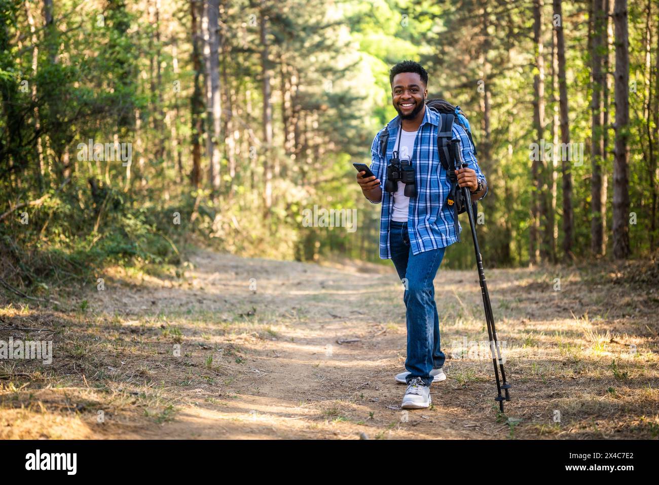 Der junge Mann liebt es, in der Natur zu wandern und das Handy zu benutzen. Stockfoto