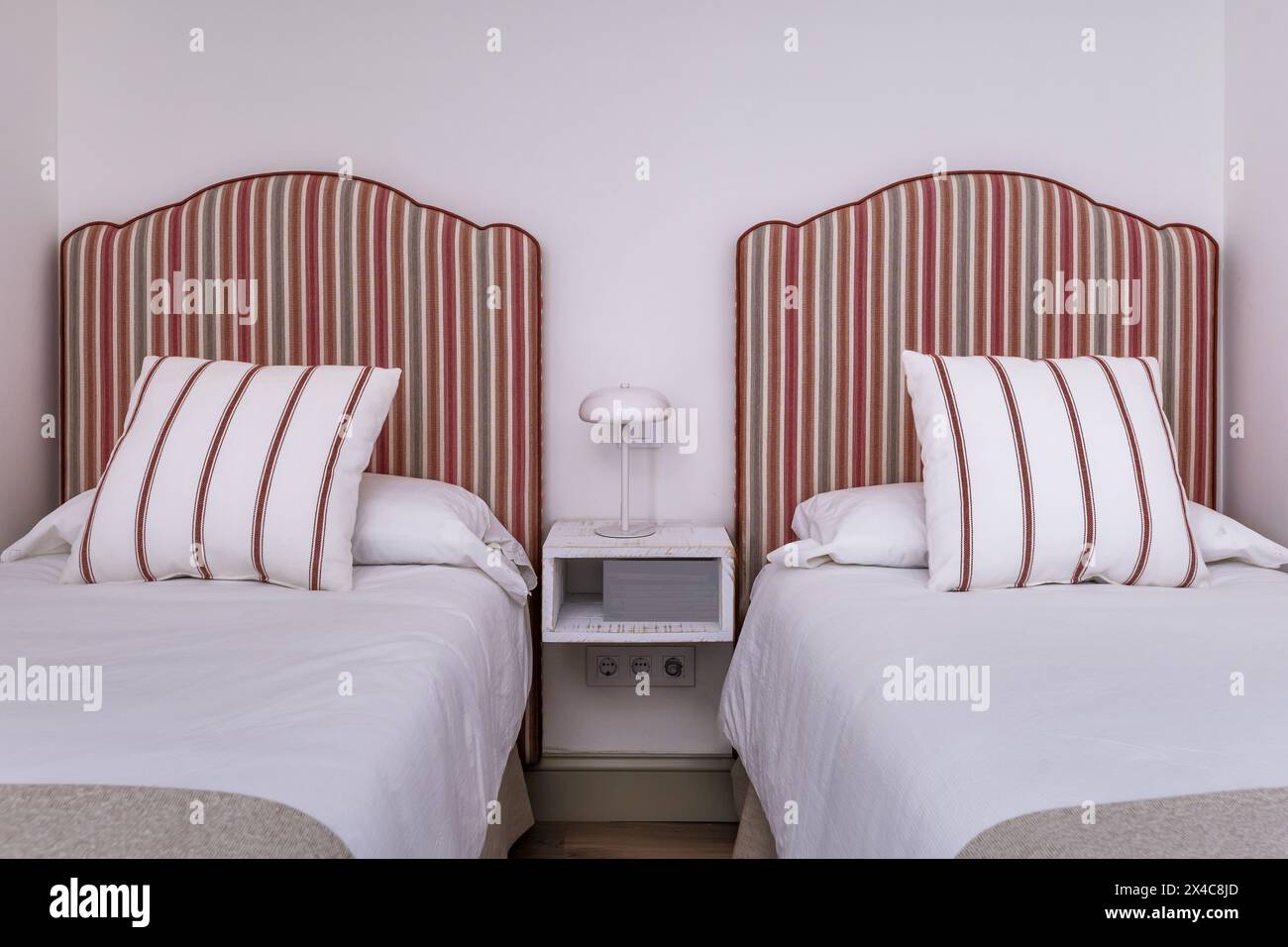 Schlafzimmer mit Twin-Betten, Kopfteilen mit überwiegend rot gestreiftem Stoff und hängendem Nachttisch aus Holz Stockfoto