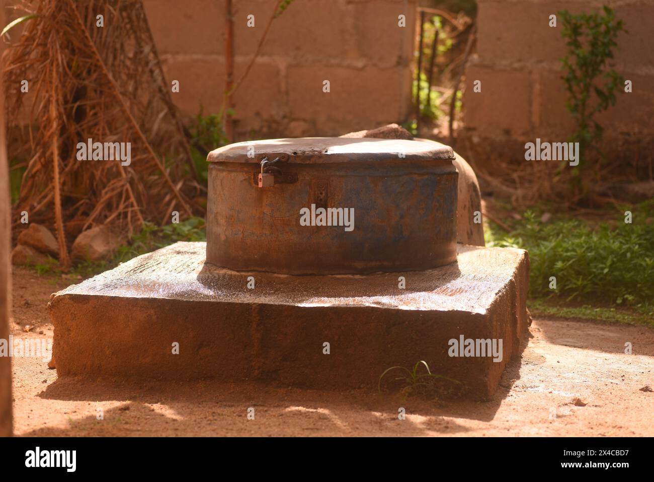 Ein ländlicher Brunnen mit Betonsockel und gusseiserner Abdeckung Stockfoto