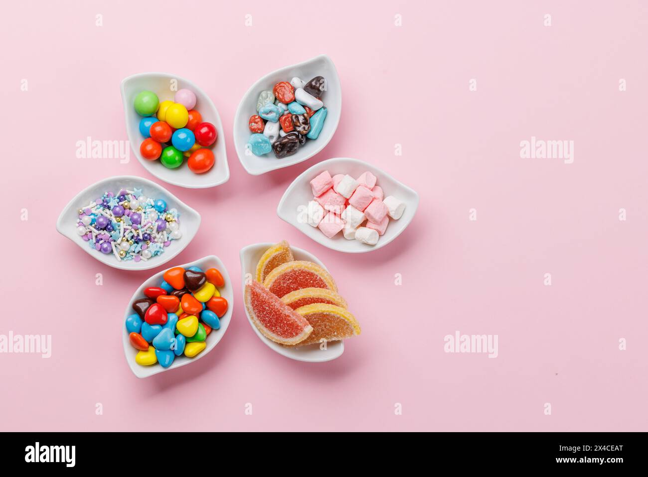 Verschiedene bunte Süßigkeiten, Lutscher. Flach über rosafarbenem Hintergrund mit Kopierraum Stockfoto