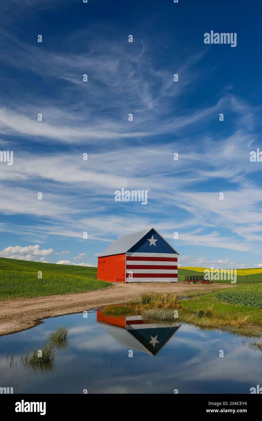 USA, Idaho, Genesee. Scheune in Rot, weiß und Blau und Reflexion in einem kleinen Teich Stockfoto