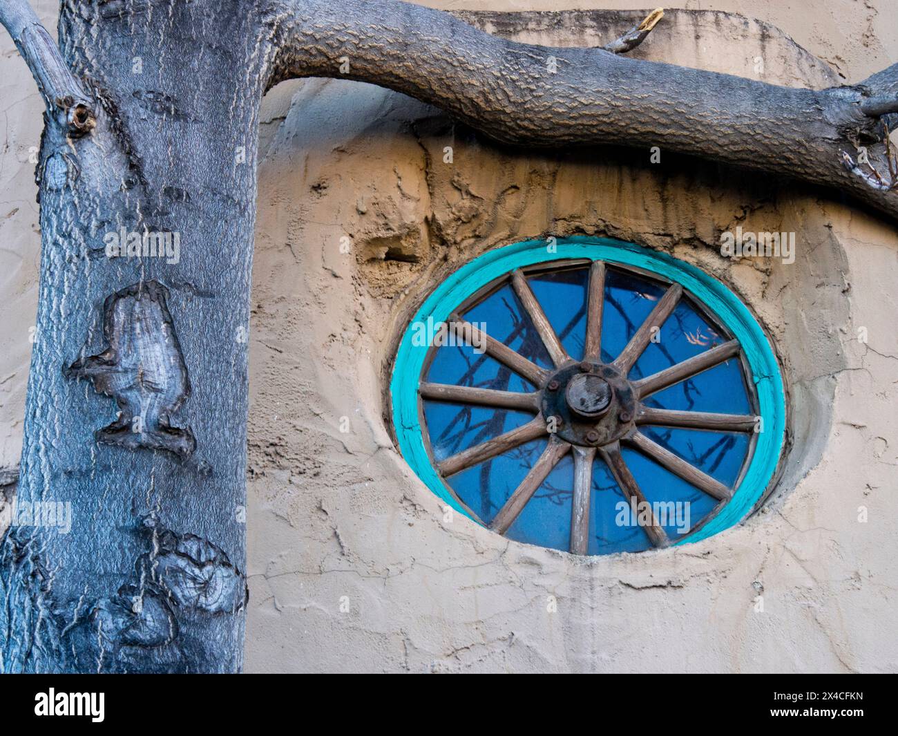 USA, New Mexico, Sante Fe. Dekoratives türkisfarbenes Wagenradfenster an einem alten lehmhaus. Stockfoto