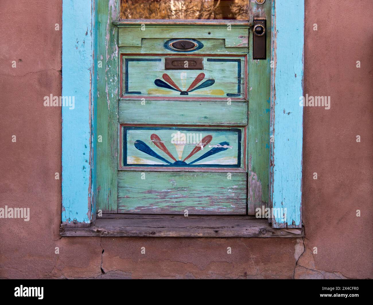 USA, New Mexico, Sante Fe. Unterer Teil einer farbenfrohen Holztür mit handgemalten Kunstwerken. Stockfoto