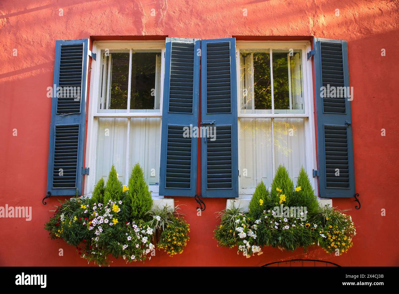 Charleston, South Carolina, USA. Rotes historisches Haus mit Plantagenläden und blühenden Blumenkästen Stockfoto