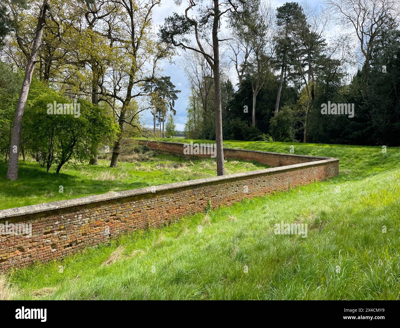 Eine Backsteinmauer auf einem Landgut zeigt den Umkreis, der einen Wald umschließt. Stockfoto