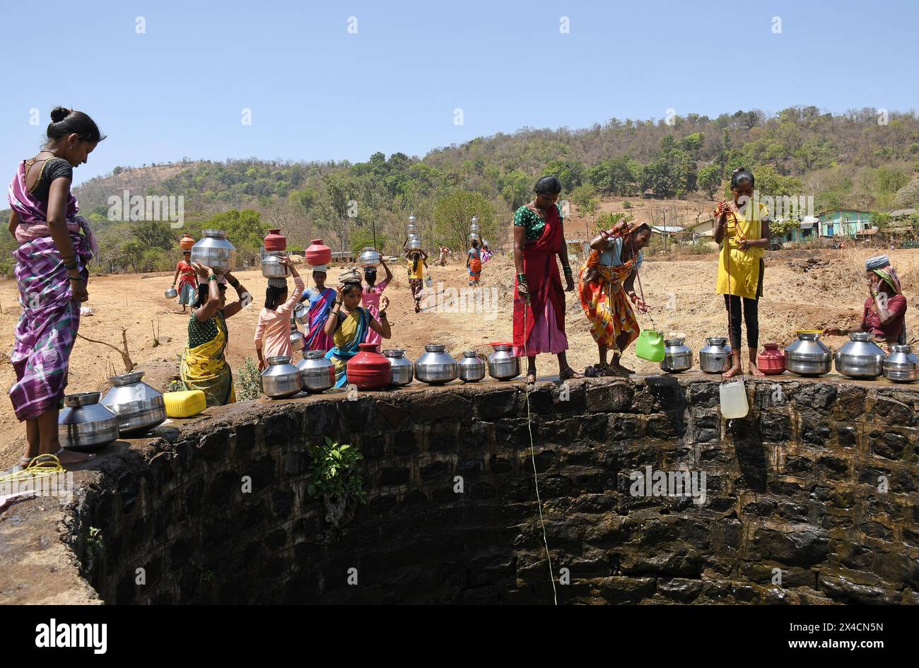 Mumbai, Indien. Mai 2024. Die Dorfbewohner werden gesehen, wie sie Wasser aus dem Brunnen in der Nähe des Dorfes Vihigaon, Shahapur taluka im Bezirk Thane, am Stadtrand von Mumbai füllen. Jedes Jahr in den Sommermonaten sind viele Dörfer in Shahapur taluka im Bezirk Thane mit einem akuten Wassermangel konfrontiert. Nach Angaben der Dorfbewohner wird trotz des Flusses Vaitarna, der nur wenige Kilometer vom Dorf entfernt ist, Wasser aus dem Fluss für die Nutzung in Mumbai umgeleitet und so den Dorfbewohnern während der Sommersaison jedes Jahr Wasser entzogen. Quelle: SOPA Images Limited/Alamy Live News Stockfoto