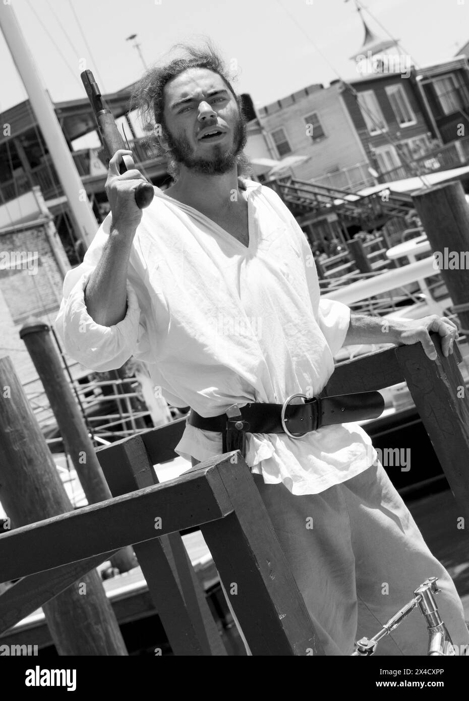 Ein Pirat in voller Kostümierung schießt eine Pistole vom Deck des Jolly Rover Großschiffs, das am Flussufer in Georgetown, South Carolina, USA, angedockt ist. Stockfoto