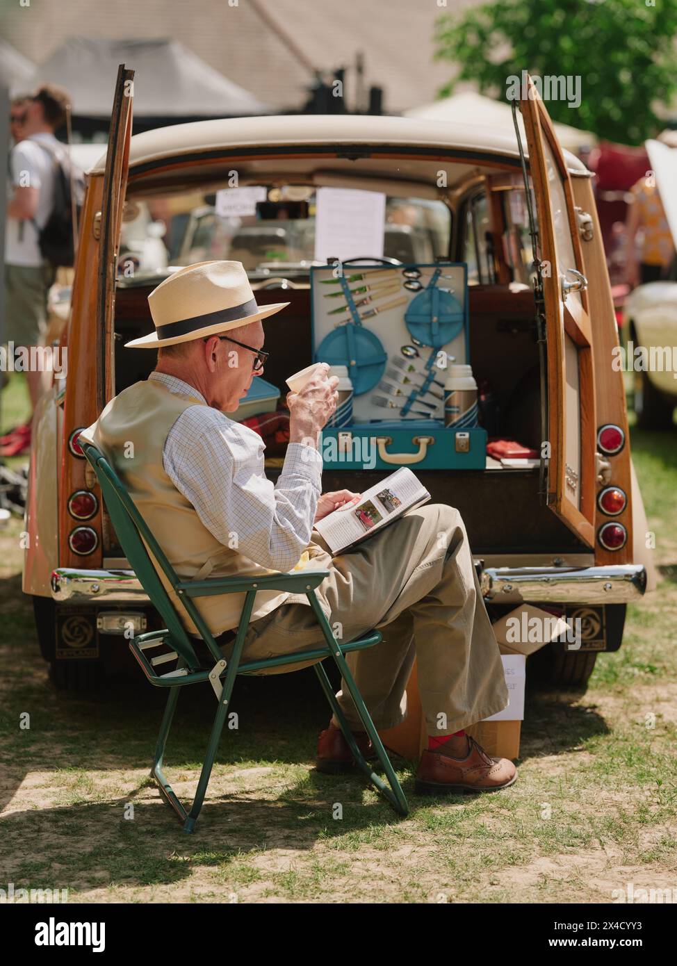 Oldtimer-Besitzer, der sich auf einer Oldtimer-Show in England, Großbritannien, entspannt - Haslemere Classic Car Show Mai 2023 - British Life trinkt Tee Stockfoto
