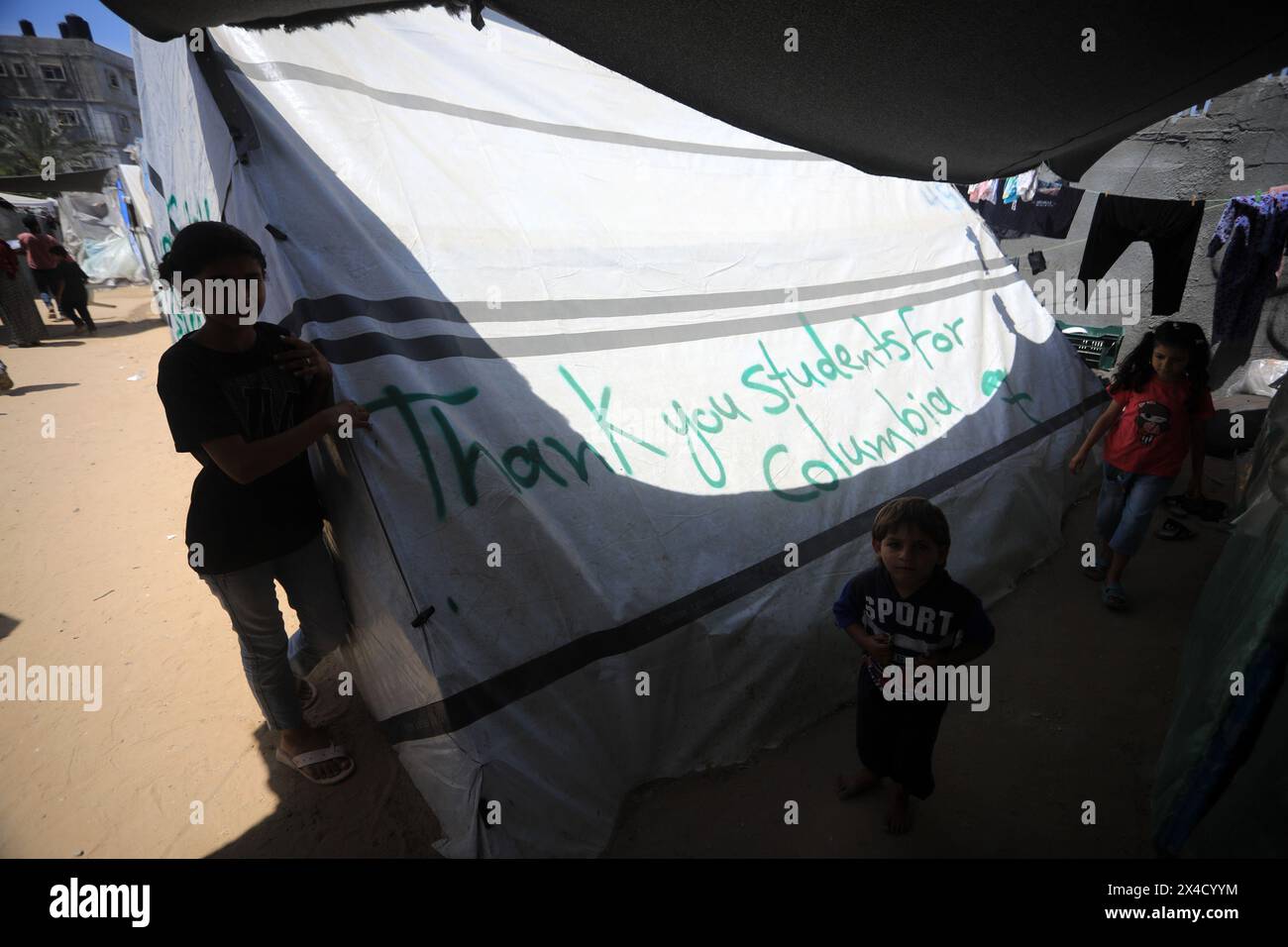 Rafah, Gaza. Mai 2024. Vertriebene palästinensische Kinder laufen am Donnerstag, den 2. Mai 2024, in Rafah im Gazastreifen an einem Zelt vorbei, das mit Slogans geschmückt ist, die den amerikanischen Studenten für ihre Unterstützung der Palästinenser und die Verurteilung des israelischen Krieges gegen Gaza danken. Foto: Ismael Mohamad/UPI Credit: UPI/Alamy Live News Stockfoto