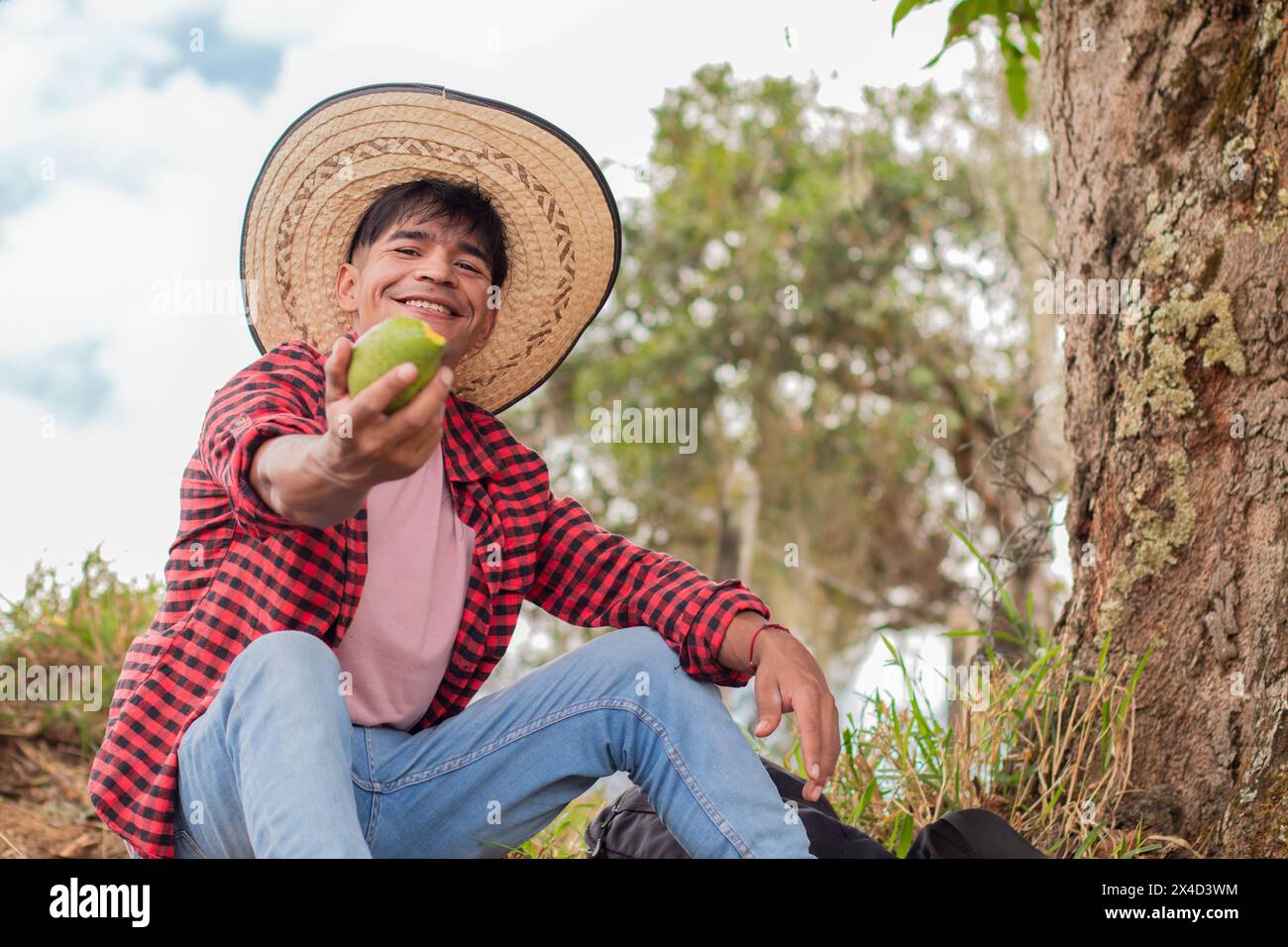 Lebensstil: lateinischer Bauer lächelt und teilt seine grüne Mango Stockfoto