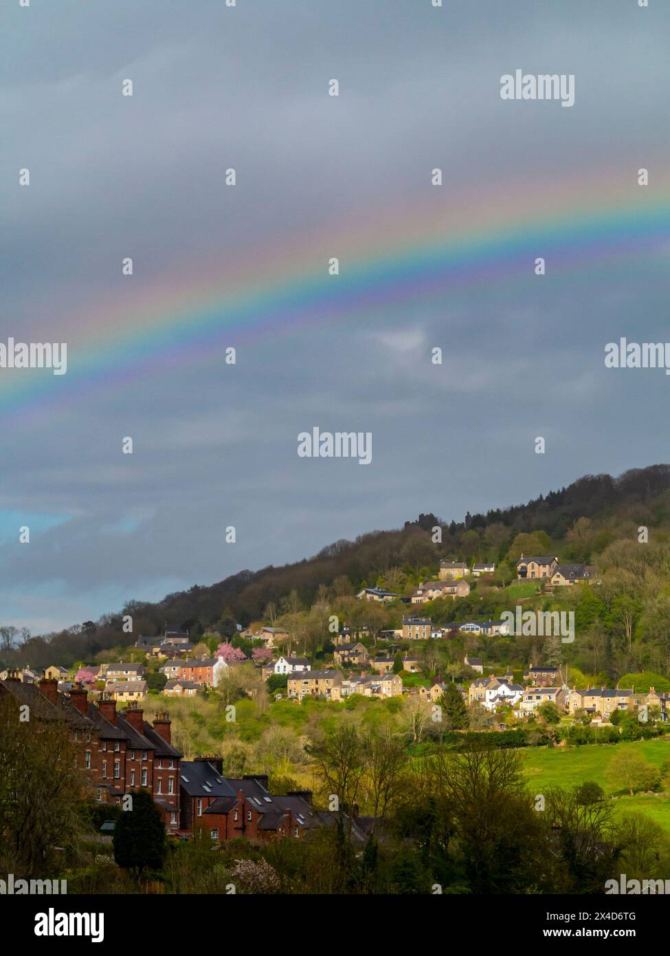 Regenbogen und stürmischer Himmel über dem Dorf Matlock Bath im Derbyshire Peak District England Großbritannien mit Starkholmes sichtbar auf dem Hügel dahinter. Stockfoto