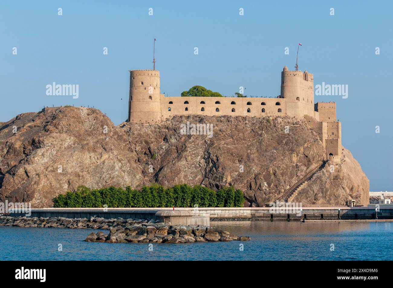 Ein Fort auf einer Klippe mit Blick auf den Sultan Qaboos Al-Alam Palast. Maskat, Oman. Stockfoto