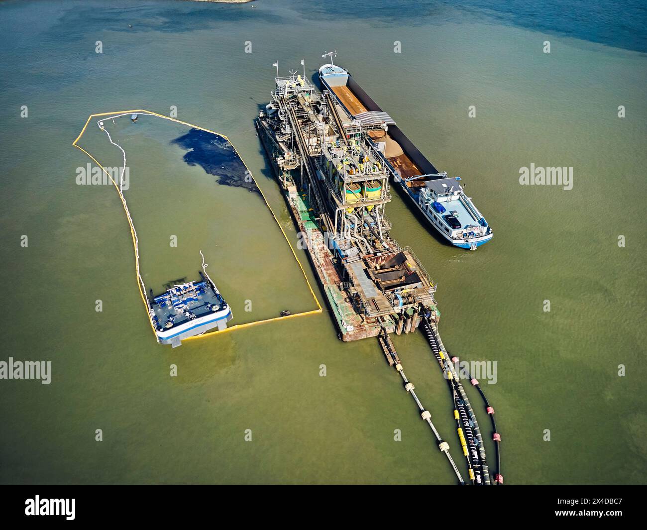 2. Mai 2024, Deest, Gelderland, Niederlande: (ANMERKUNG DER REDAKTION: Bild wird mit Drohne aufgenommen). Das Binnenschiff Courage (110 Meter lang und 50 Meter breit) brach am Mittwochmorgen beim Verladen von Sand auf einem Ausgrabungsgelände am Waal bei Deest in den Niederlanden. Austretendes Öl aus dem Behälter ist über dem Wasser sichtbar. Die niederländische Generaldirektion für öffentliche Arbeiten und Wasserwirtschaft (Rijkswaterstaat) hat Ölbooms eingeführt, um Verschmutzungen zu verhindern. Die Unfallursache ist noch unklar. (Credit Image: © Norbert Voskens/SOPA Images via ZUMA Press Wire) NUR REDAKTIONELLE VERWENDUNG! Nicht für Commer Stockfoto 2. Mai 2024, Deest, Gelderland, Niederlande: (ANMERKUNG DER REDAKTION: Bild wird mit Drohne aufgenommen). Das Binnenschiff Courage (110 Meter lang und 50 Meter breit) brach am Mittwochmorgen beim Verladen von Sand auf einem Ausgrabungsgelände am Waal bei Deest in den Niederlanden. Austretendes Öl aus dem Behälter ist über dem Wasser sichtbar. Die niederländische Generaldirektion für öffentliche Arbeiten und Wasserwirtschaft (Rijkswaterstaat) hat Ölbooms eingeführt, um Verschmutzungen zu verhindern. Die Unfallursache ist noch unklar. (Credit Image: © Norbert Voskens/SOPA Images via ZUMA Press Wire) NUR REDAKTIONELLE VERWENDUNG! Nicht für Commer Stockfoto