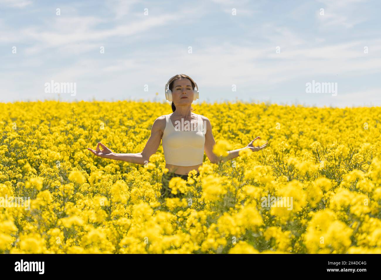 Frau meditiert und übt Yoga auf einer Wiese voller bunter gelber Blumen. Geistige Entspannung in der Natur Stockfoto