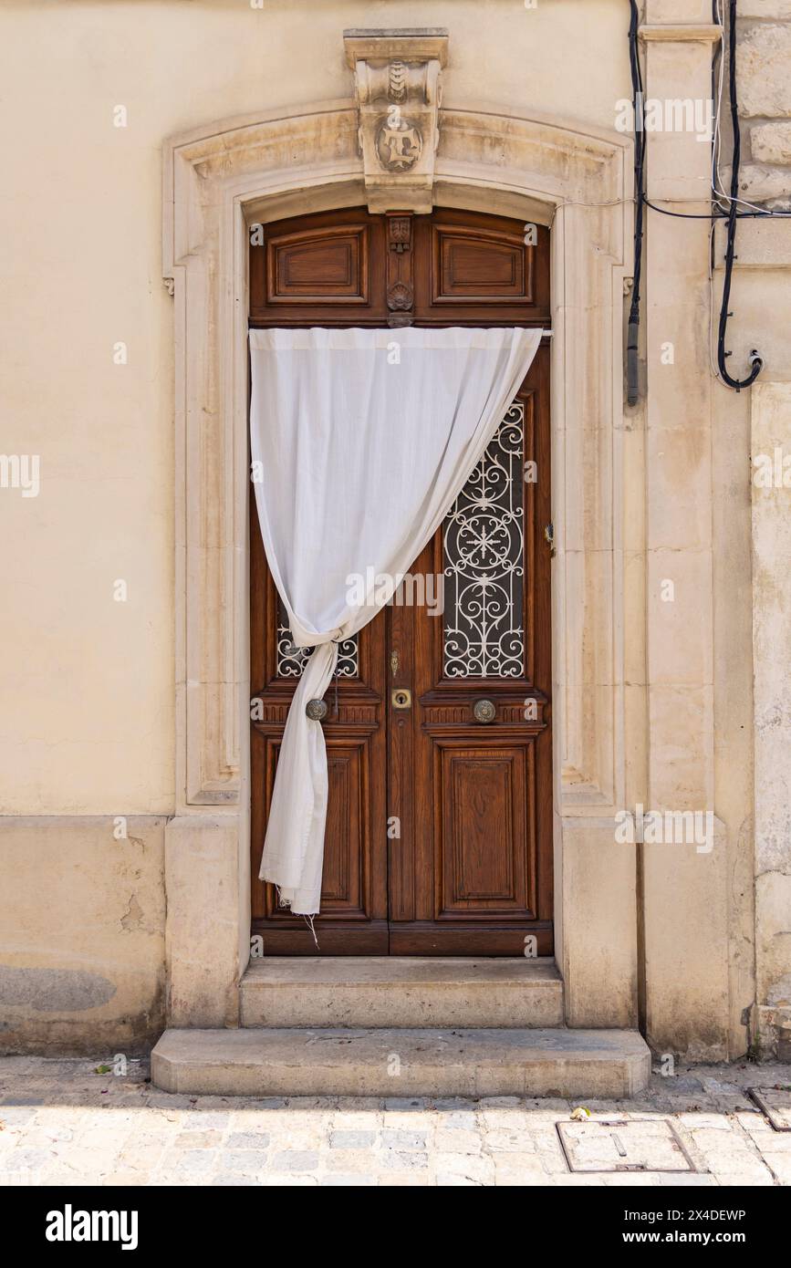 Aigues-Mortes, Gard, Okzitanien, Frankreich. Weißes Tuch, das über einer alten Holztür hing. Stockfoto