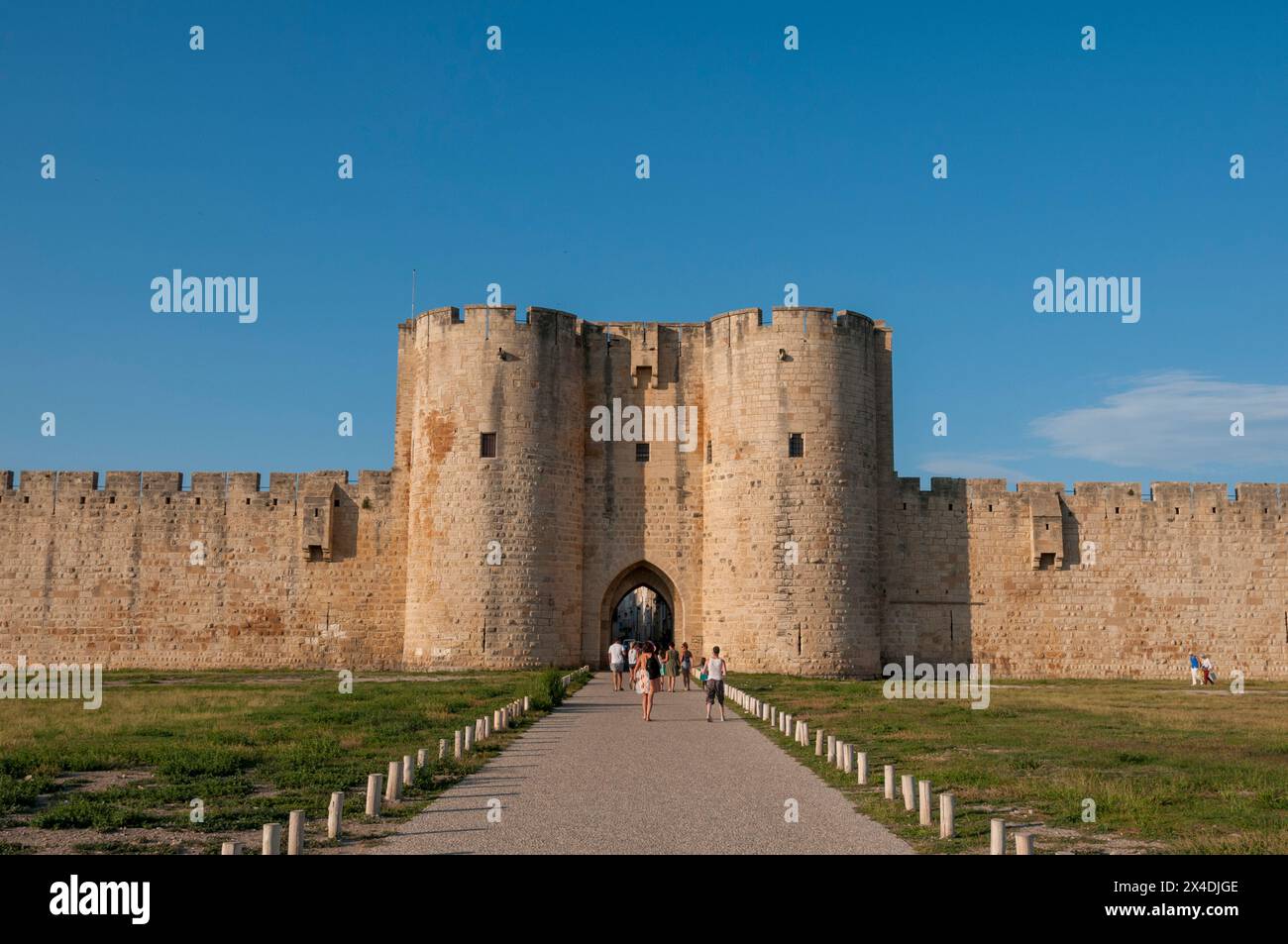 Touristen betreten das Tor an der Stadtmauer von Aigues Mortes. Gard, Languedoc Roussillon, Frankreich. Stockfoto