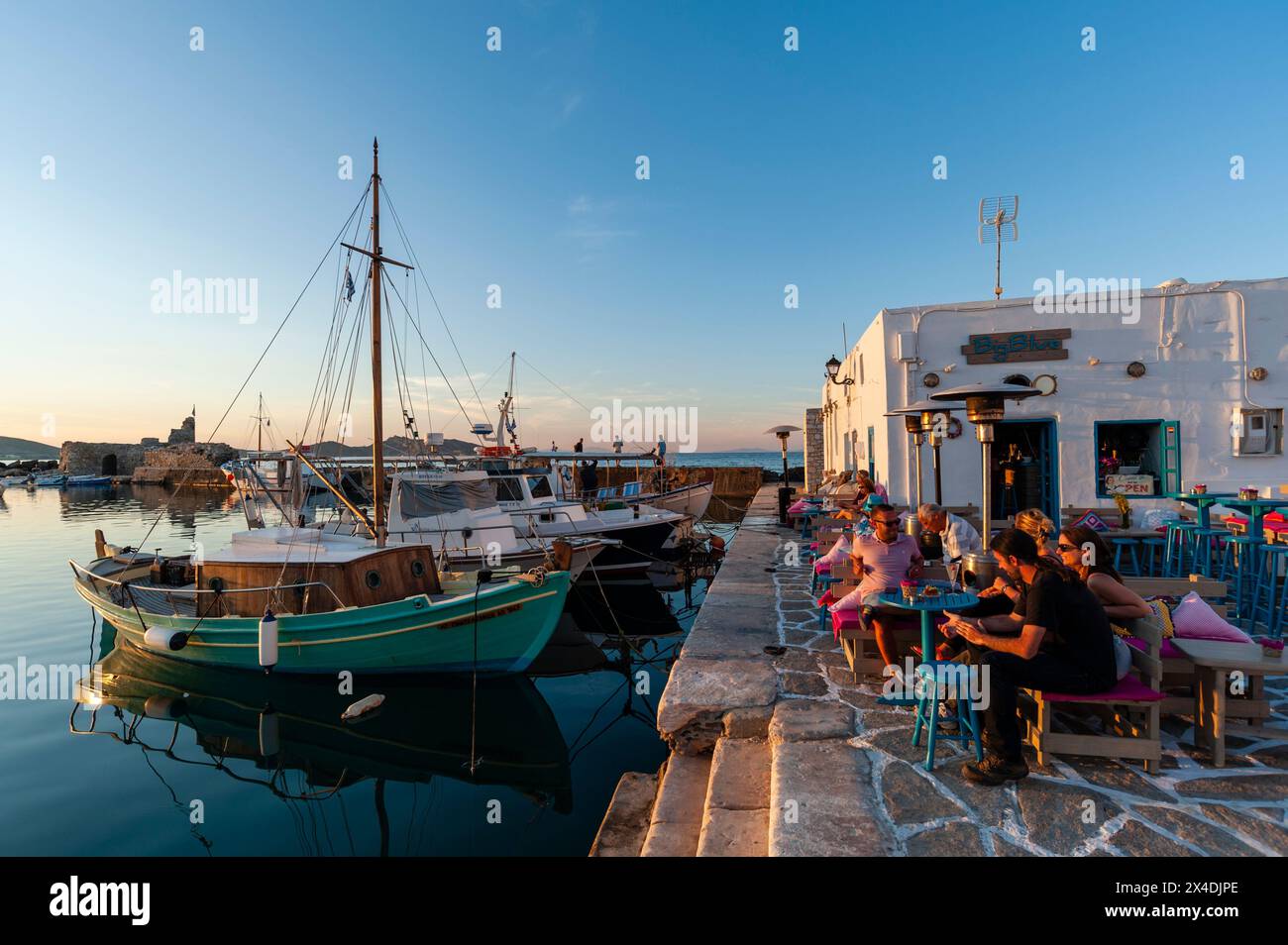 Gäste entspannen sich in einem Café im Freien im Hafen von Naousa, Paros Island, Kykladen, Griechenland. (Nur Für Redaktionelle Zwecke) Stockfoto
