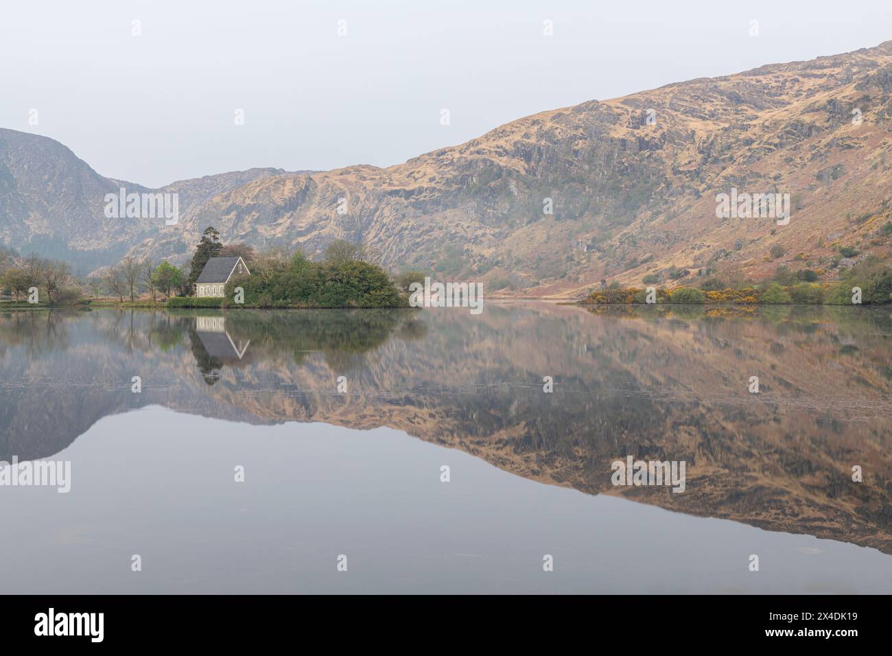 Irland, Cork, Gougane Barra. Kirchen- und Bergreflexionen im See. Stockfoto