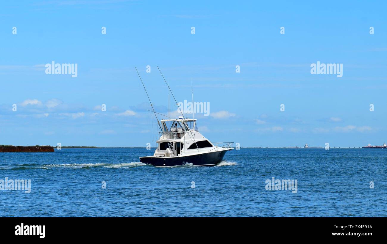 Breiter Blick auf ein wunderschönes weißes und schwarzes Fischerboot segelt auf dem ruhigen blauen Wasser an einem sonnigen Tag. Stockfoto