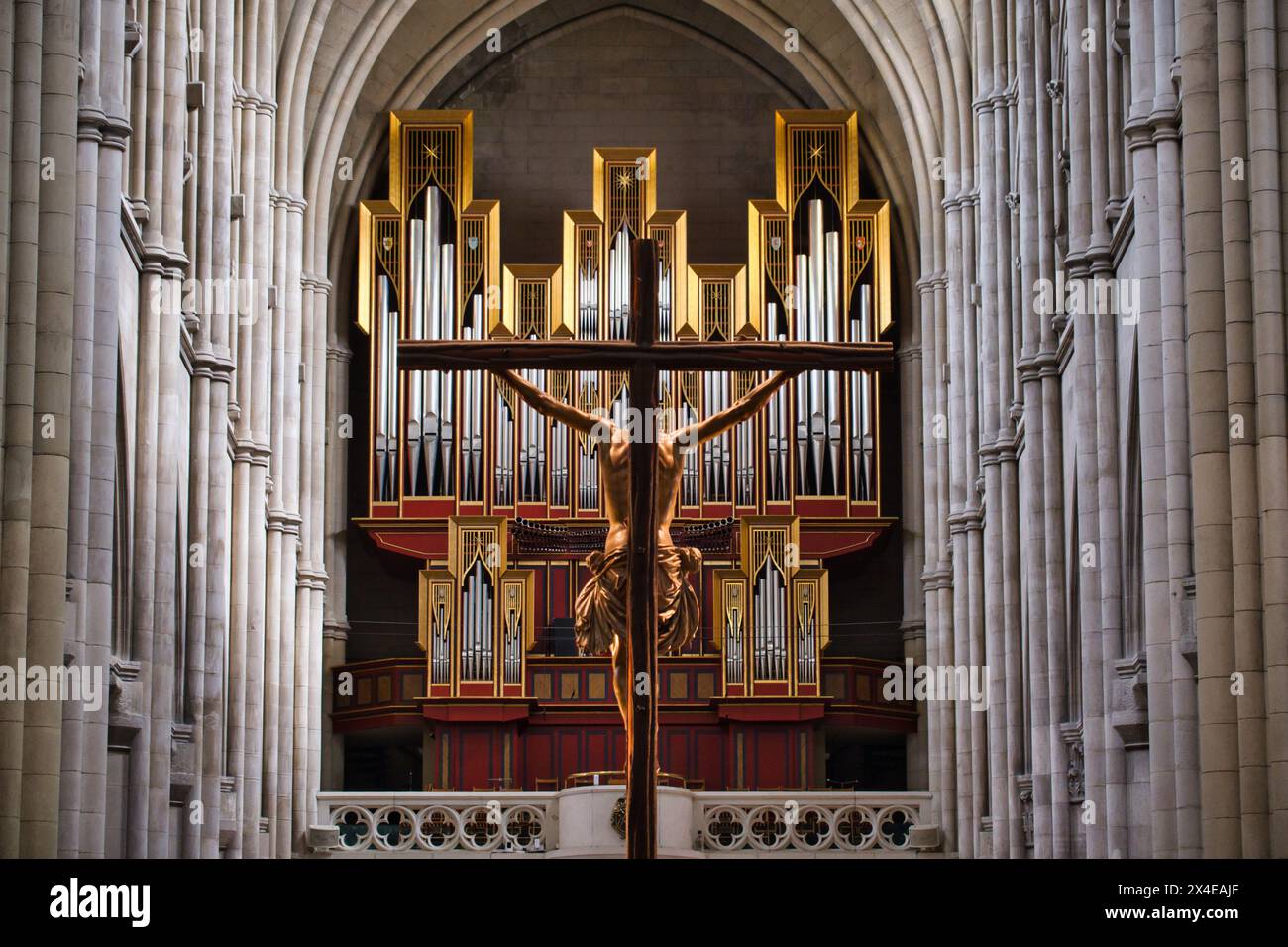 Rückansicht des Kruzifix in der Kathedrale von Almudena in Madrid mit den Orgelpfeifen im Hintergrund. Kontrast zwischen Schmerz und Reichtum Stockfoto