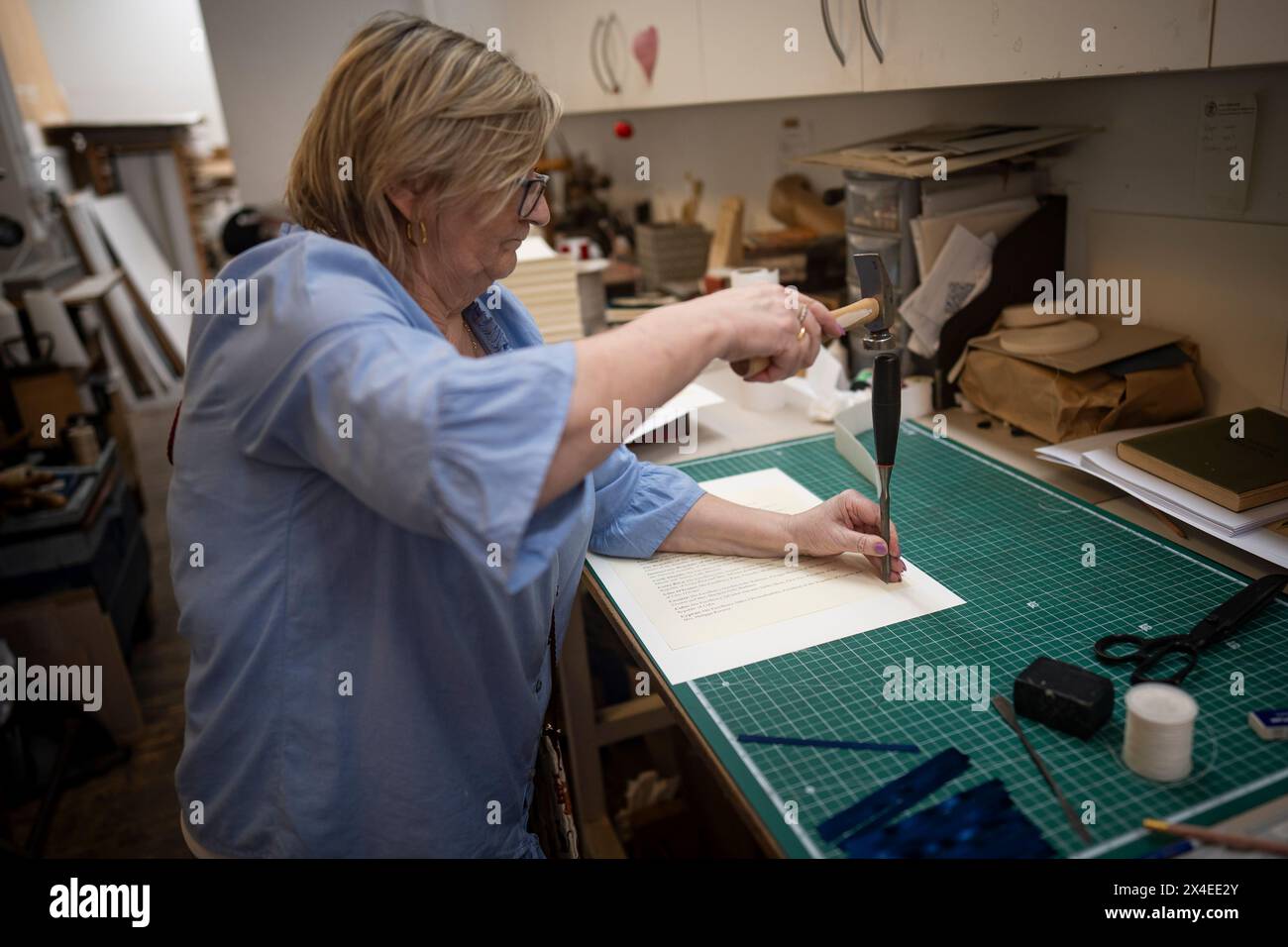 Die Schlitze werden von Janet Rowe in Seiten geschnitten und können auf die Krönungsrolle von König Karl III. Bei Shepherds Bookbinders, London, gelegt und genäht werden. Bilddatum: Donnerstag, 11. April 2024. Stockfoto