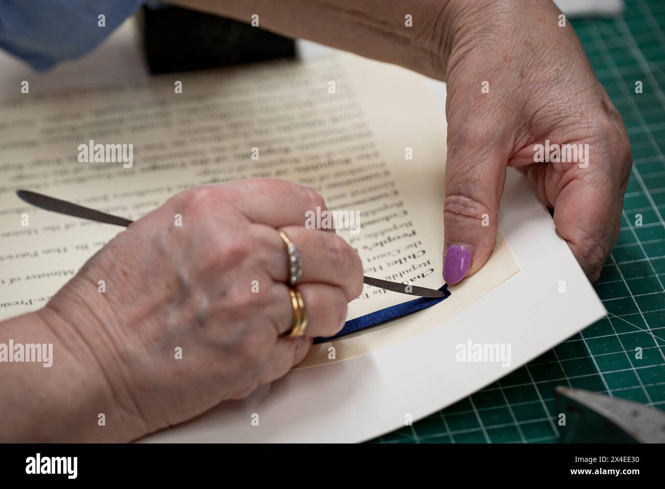 Das Band wird von Janet Rowe in Seiten eingefädelt und kann auf die Krönungsrolle von König Karl III. Bei Shepherds Bookbinders in London aufgenäht werden. Bilddatum: Donnerstag, 11. April 2024. Stockfoto