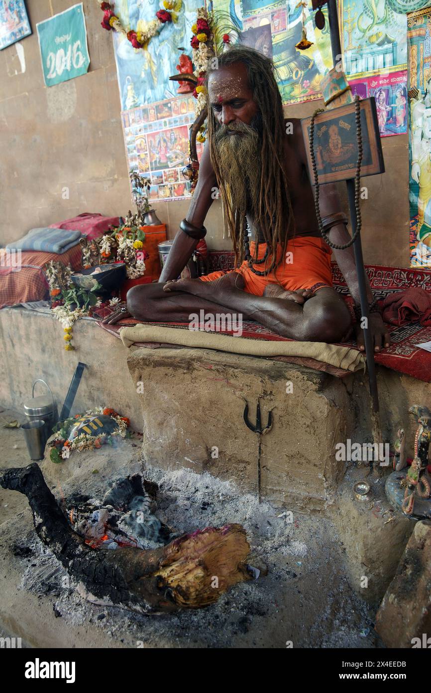 Sadhu oder spiritueller Aspirant sitzt in Lotusposition vor einem Feuer in Varanasi, Indien. Stockfoto