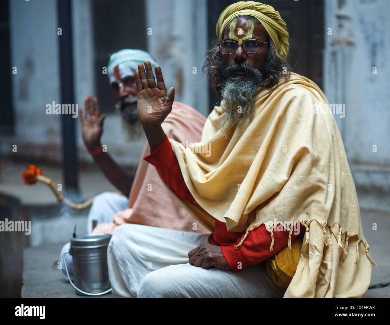 Zwei sitzende Sadhus oder spirituelle Aspiranten mit den Händen, die in einem Segen in Varanasi, Indien, erhoben wurden. Stockfoto