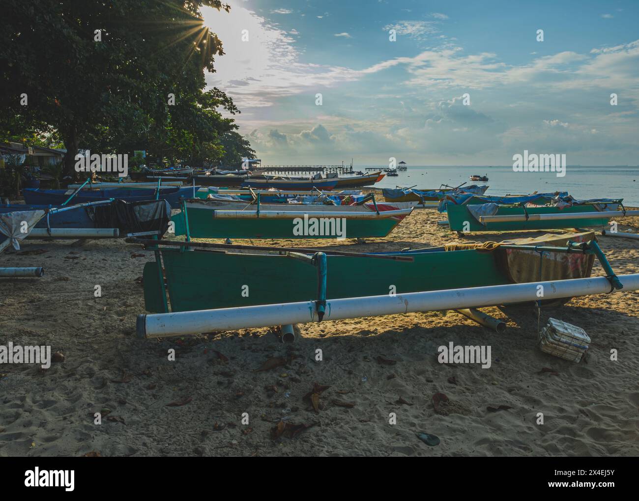 Balikpapan, Indonesien - 16. April 2024. Mehrere farbenfrohe Holzfischboote werden am Morgen an einem Sandstrand gezogen. Stockfoto