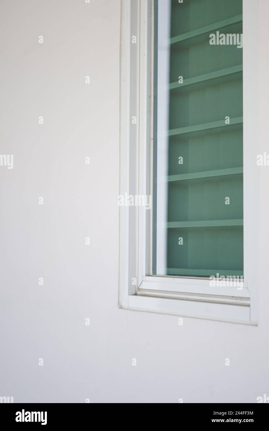 Minimalistischer Hintergrund eines langen Glasfensters mit grünen Vorhängen und weißen Wänden Stockfoto