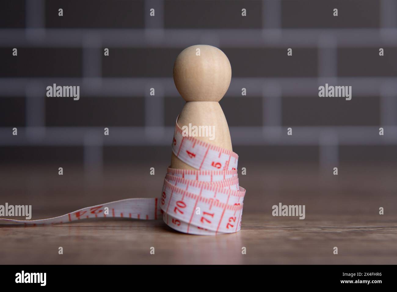 Holzpuppe und Maßband. Diät- und Gewichtsmanagement-Konzept. Kopierbereich für Text. Stockfoto