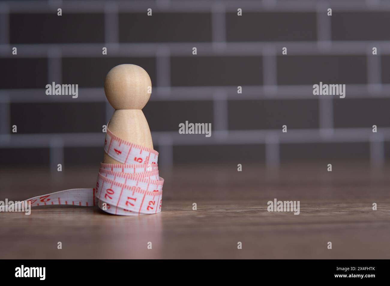 Holzpuppe und Maßband. Diät- und Gewichtsmanagement-Konzept. Kopierbereich für Text. Stockfoto