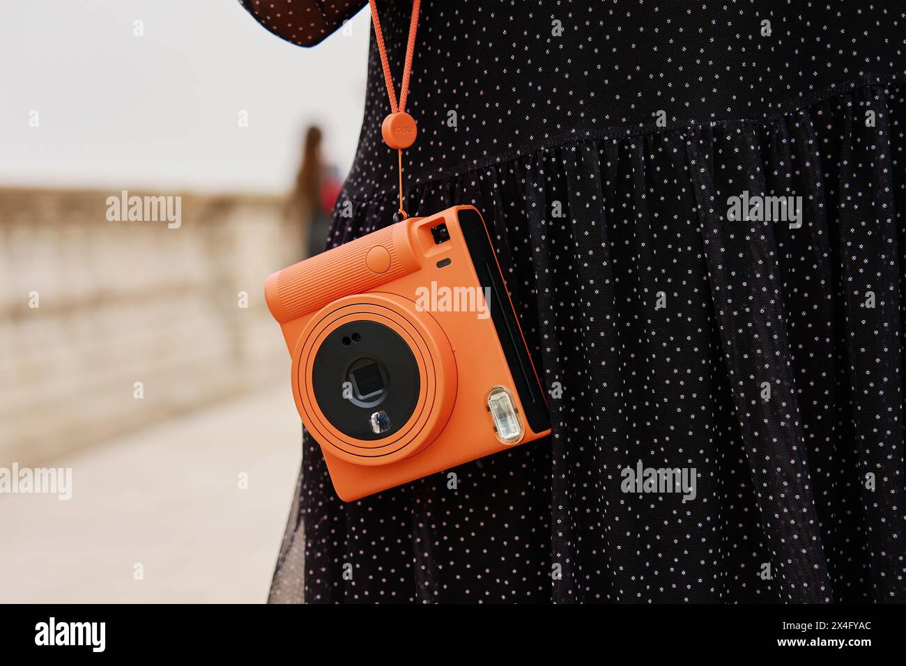 Frau mit orangefarbener Sofortkamera. Touristen halten Erinnerungen während der Reise mit einer alten Kamera fest Stockfoto