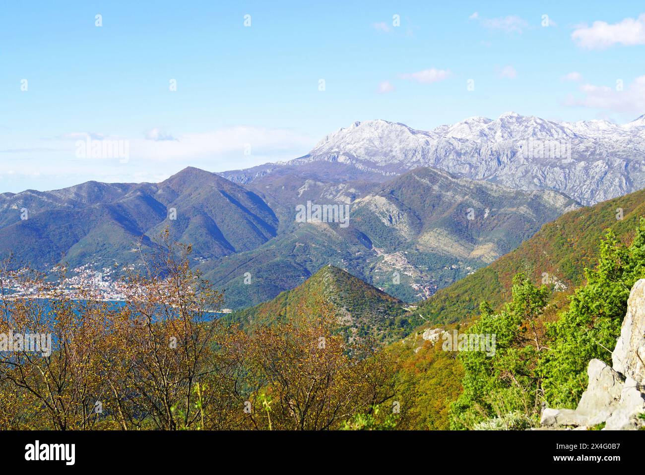Kontrastierende Landschaft im Jahreswechsel: Herbstfarben des Mount Vrmac und Winter Orjen im Hintergrund (Montenegro). Stockfoto