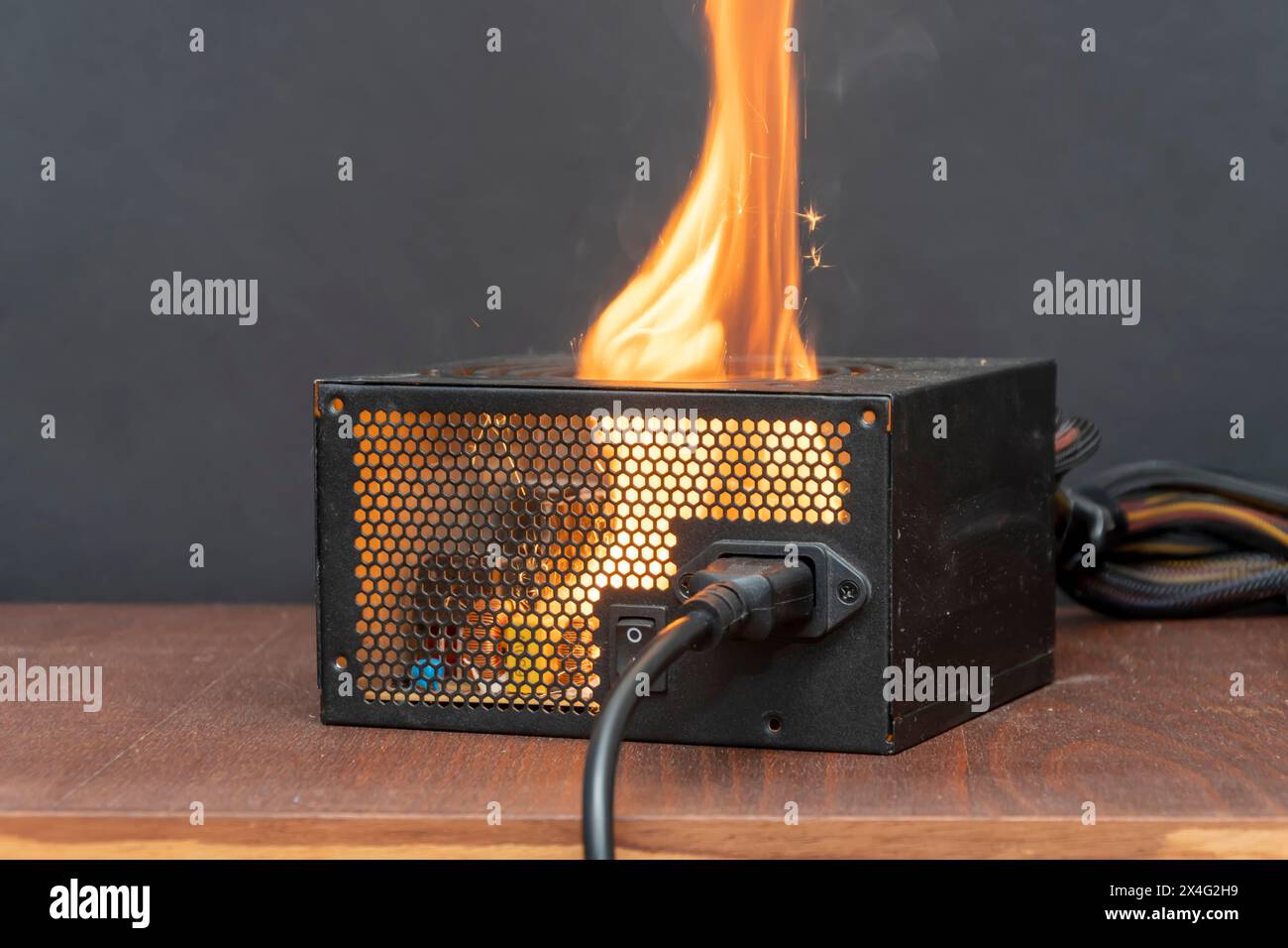 Zündung der Stromversorgung des Computers, Kurzschluss, Nahaufnahme, selektiver Fokus. Ein Feuer in der Wohnung durch elektrische Haushaltsgeräte. Stockfoto