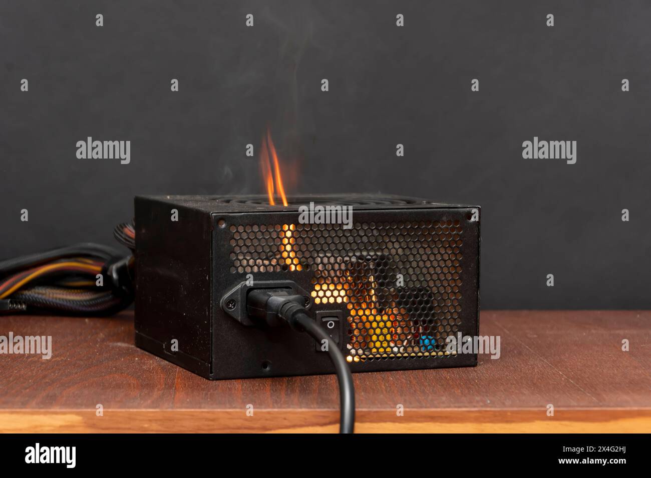 Zündung der Stromversorgung des Computers, Kurzschluss, Nahaufnahme, selektiver Fokus. Ein Feuer in der Wohnung durch elektrische Haushaltsgeräte. Stockfoto