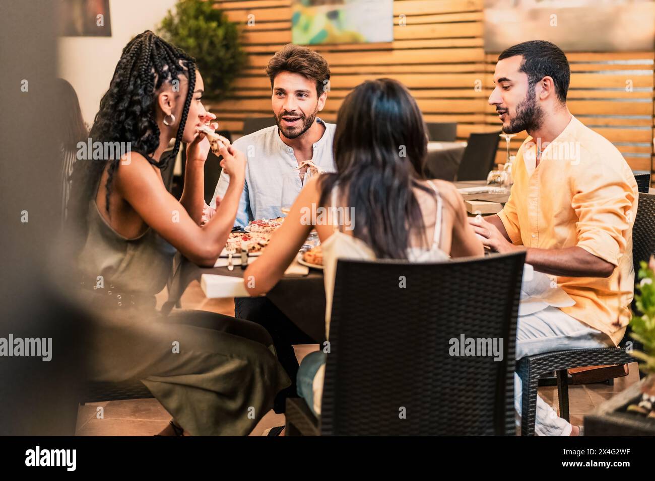 Vielfältige Gruppe von Freunden - Abendessen und Unterhaltung in einem Restaurant genießen, eine Mahlzeit in einer lebhaften städtischen Umgebung teilen - gesellig, unterhaltsam. Stockfoto