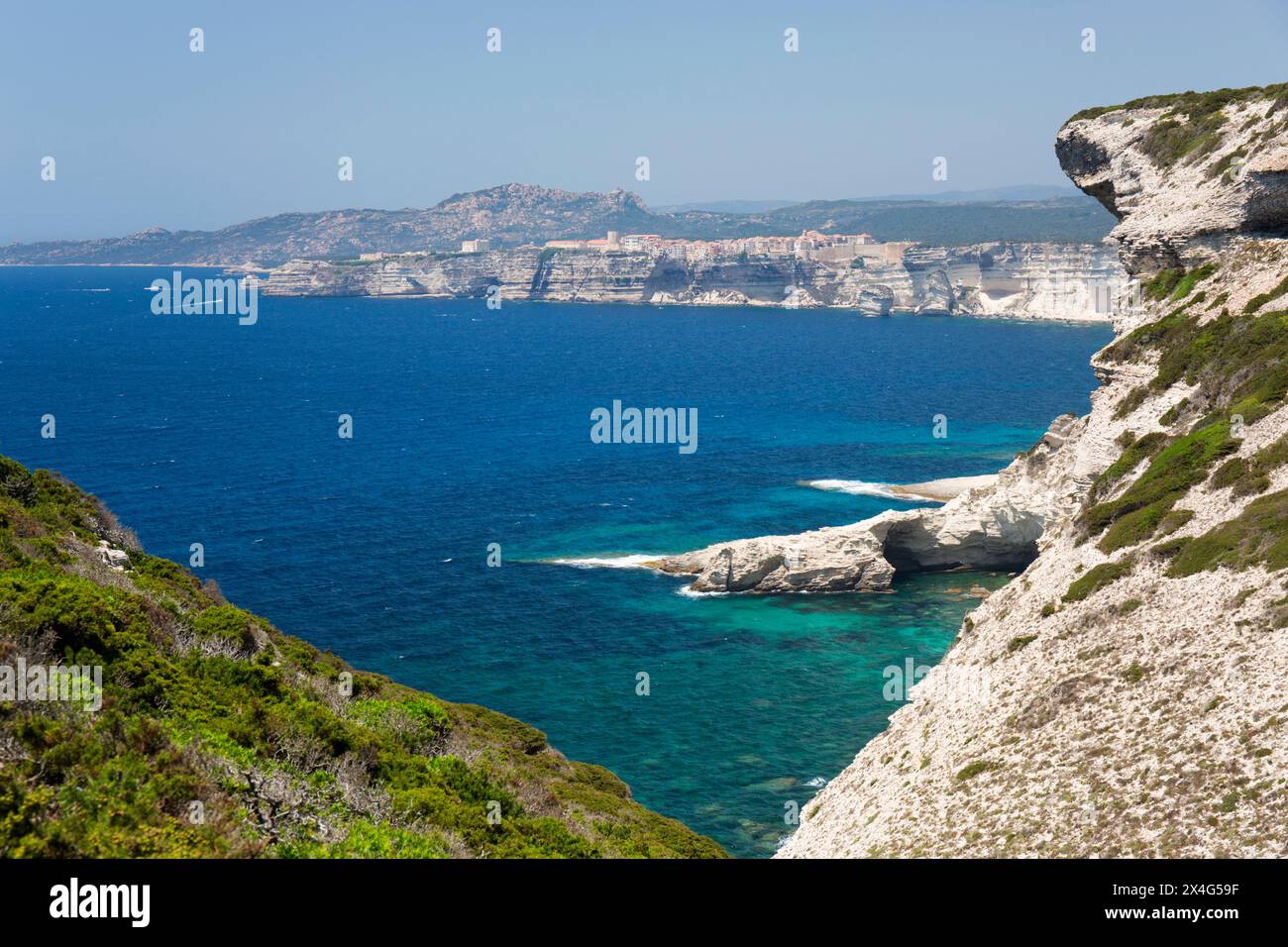 Bonifacio, Corse-du-Sud, Korsika, Frankreich. Blick entlang zerklüfteter Kalksteinklippen in der Nähe von Capo Pertusato bis zur fernen Zitadelle. Stockfoto