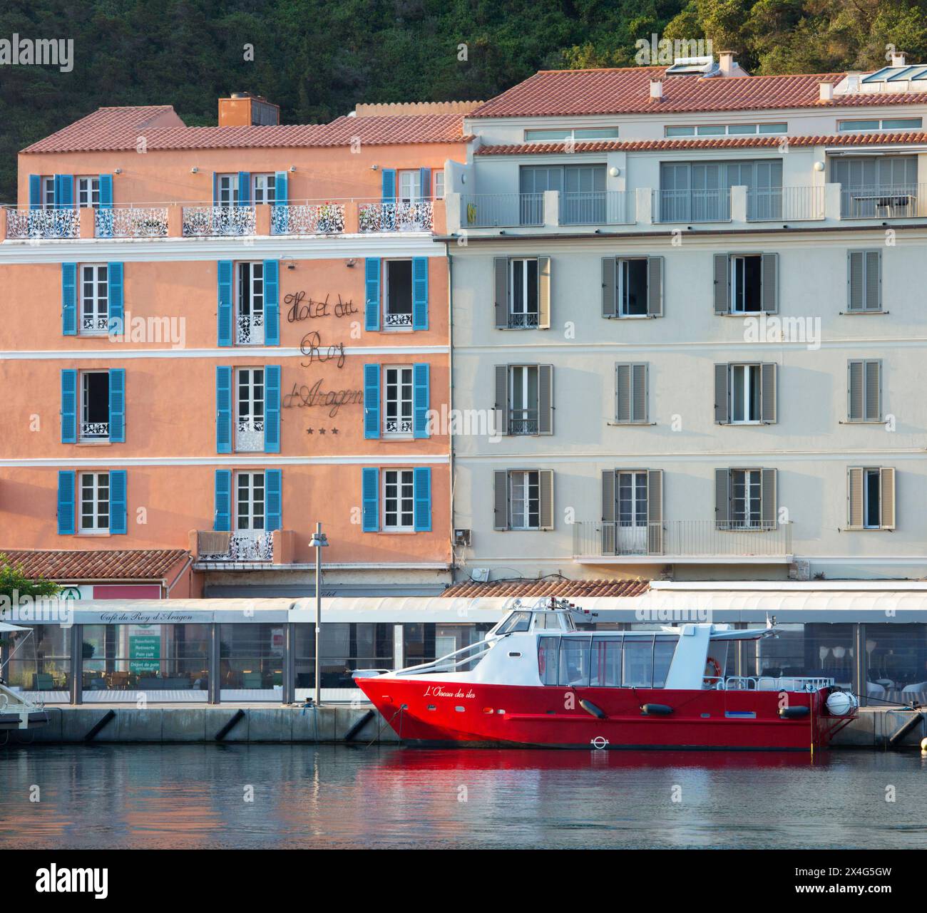 Bonifacio, Corse-du-Sud, Korsika, Frankreich. Blick vom Kai über den Hafen auf die pastellrosa Fassade des Hôtel du Roy d'Aragon, Sonnenaufgang. Stockfoto