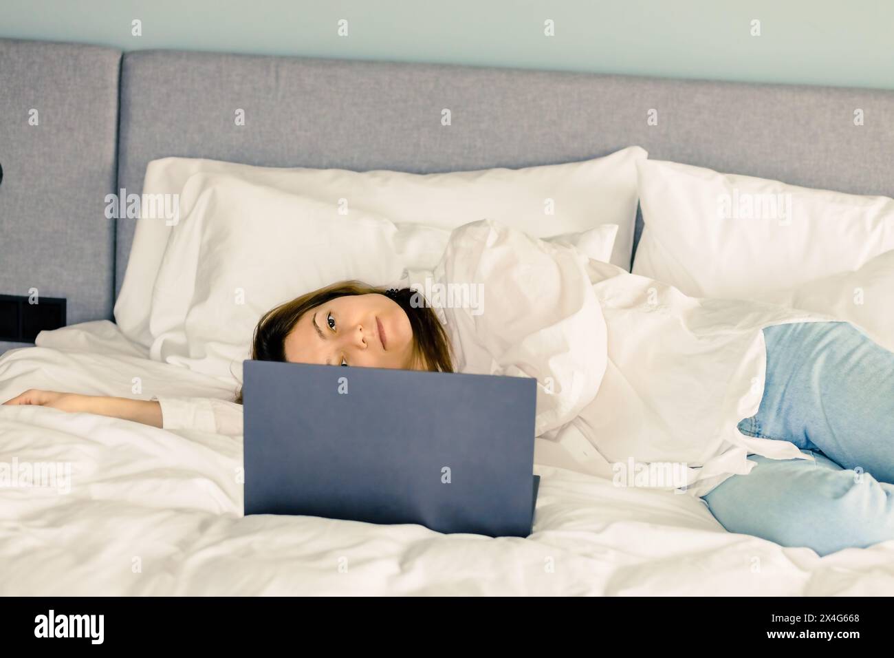 Frau mit Laptop, die zu Hause im Bett arbeitet Stockfoto