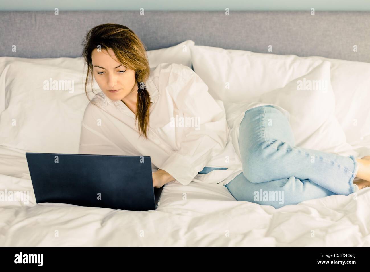 Frau mit Laptop, die zu Hause im Bett arbeitet Stockfoto