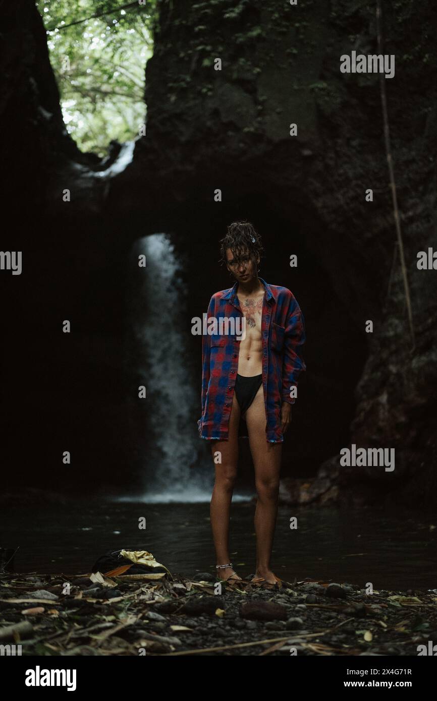 Eine junge Frau zieht sich an, nachdem sie in einem Wasserfall geschwommen ist. Stockfoto