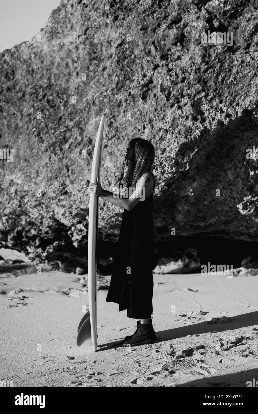 Frau mit Surfbrett, die am Strand steht Stockfoto