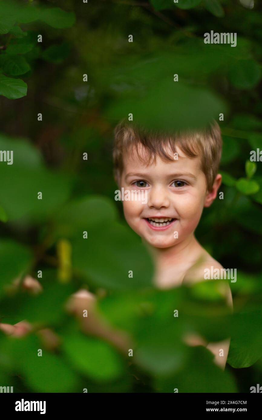 Kleiner Junge, der glücklich ist, in Waldblättern zu spielen Stockfoto