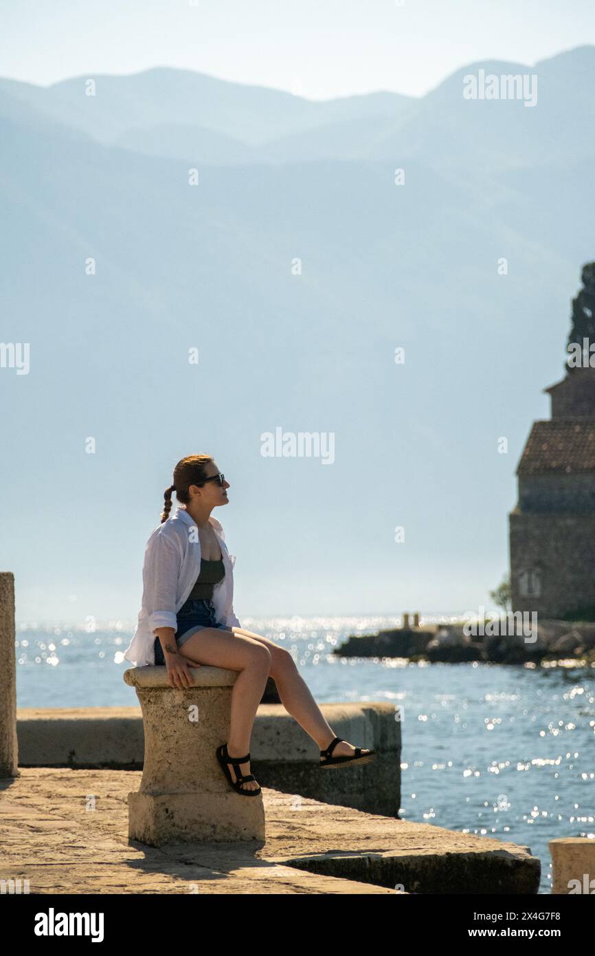 Eine Frau, die auf einer Insel in Kotor Bay sitzt Stockfoto
