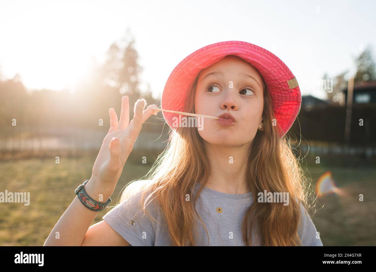 Mädchen, das an einem Sommertag draußen mit Kaugummi spielt Stockfoto