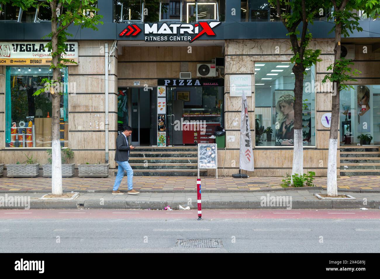 Person, die auf der Straße vor dem Matrix Fitness Center im Stadtzentrum von Tirana, Albanien, Europa läuft Stockfoto